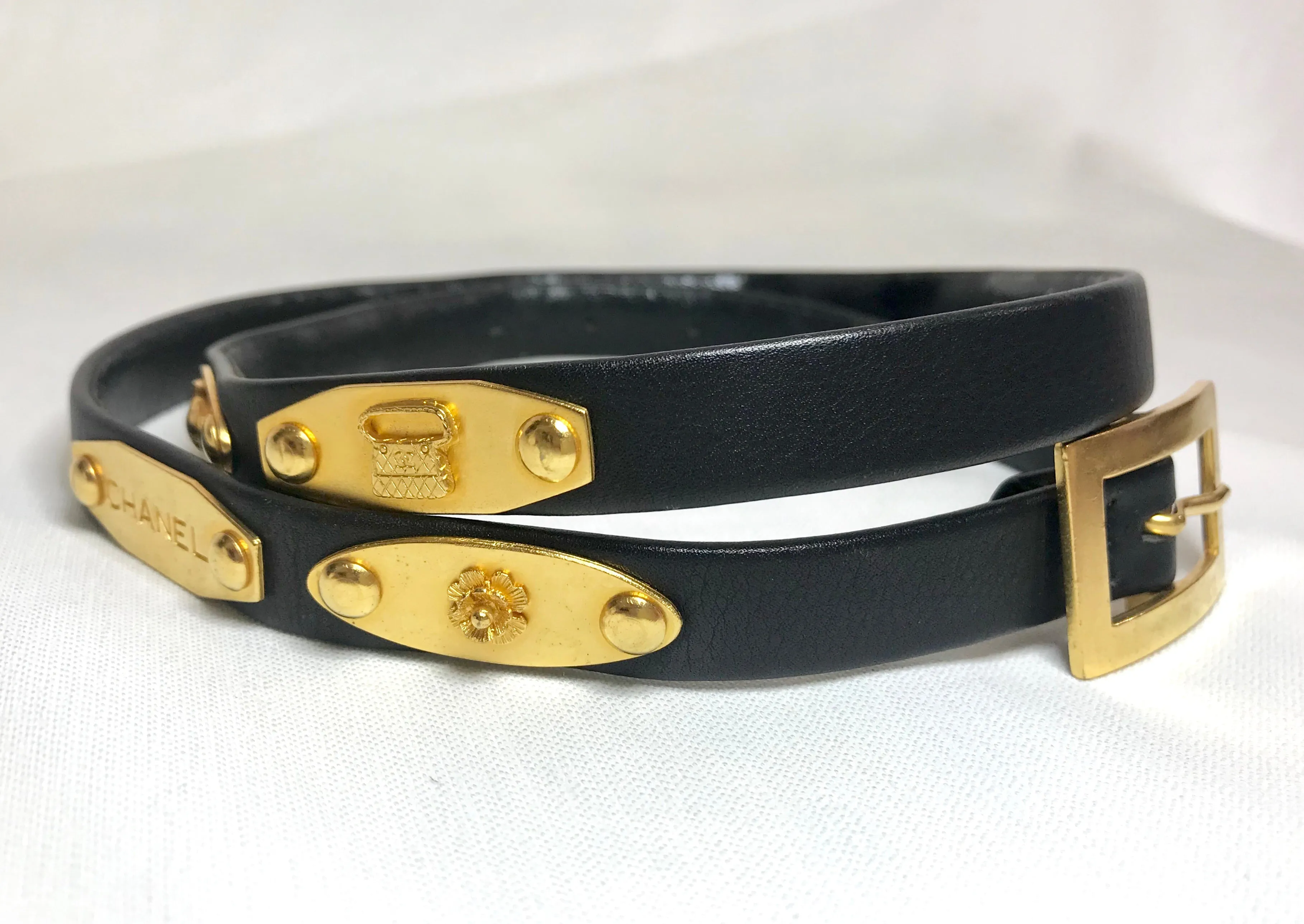 Vintage CHANEL black belt with golden buckle and iconic logo motifs, CC mark, camellia flower, turtle, perfume, clover. R0410113